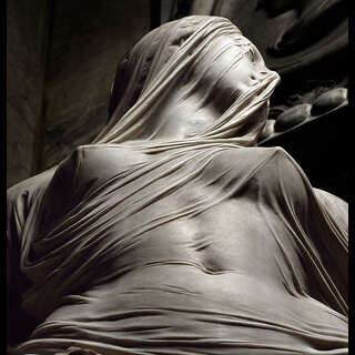 A female statue, depicting a maiden covered in thin fabric.