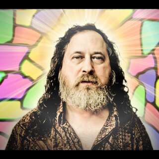 Richard M. Stallman, St IGNUcius himself in front of stained glass with a golden halo.